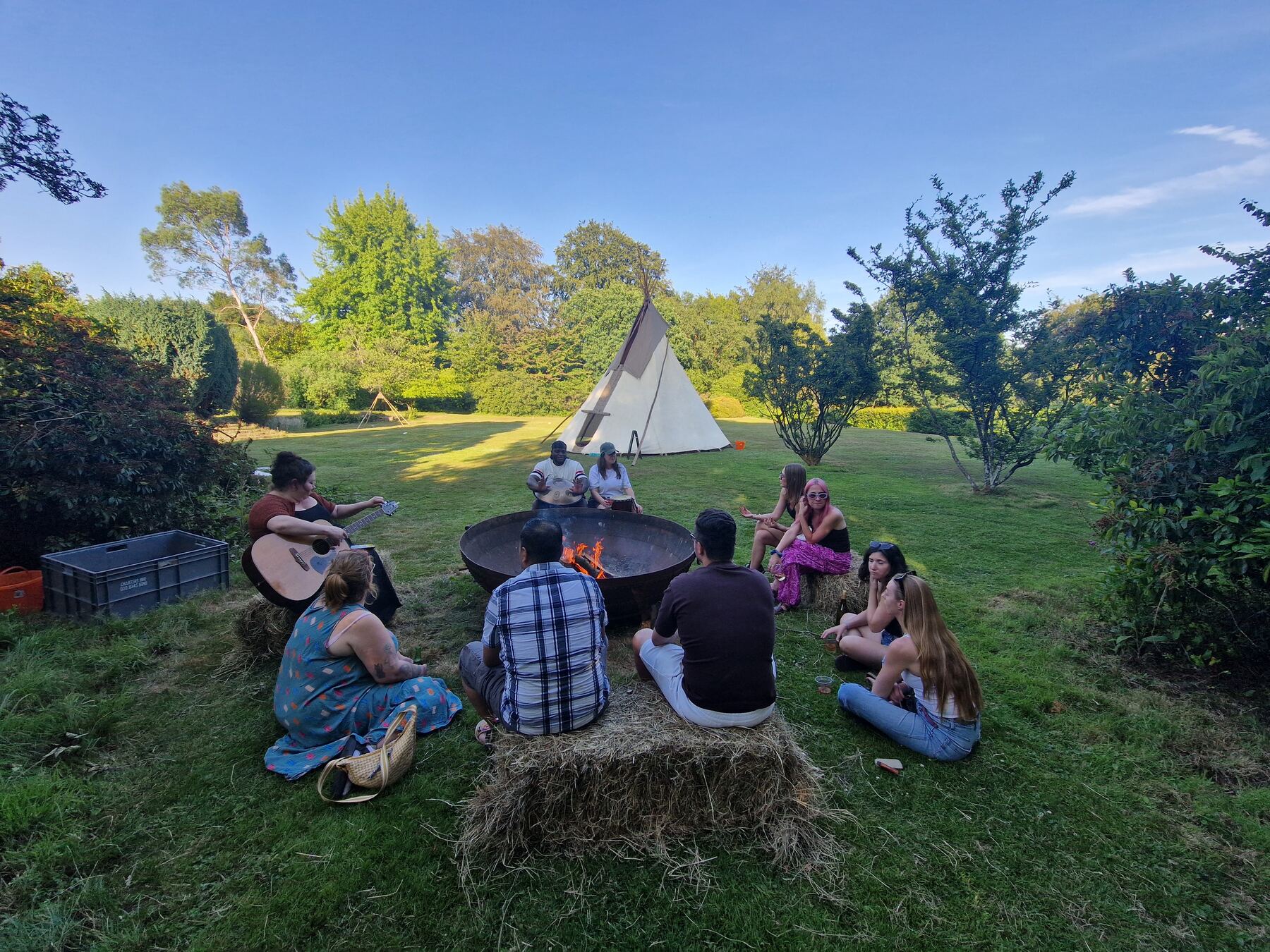People sitting on straw bales around a fire in the evening