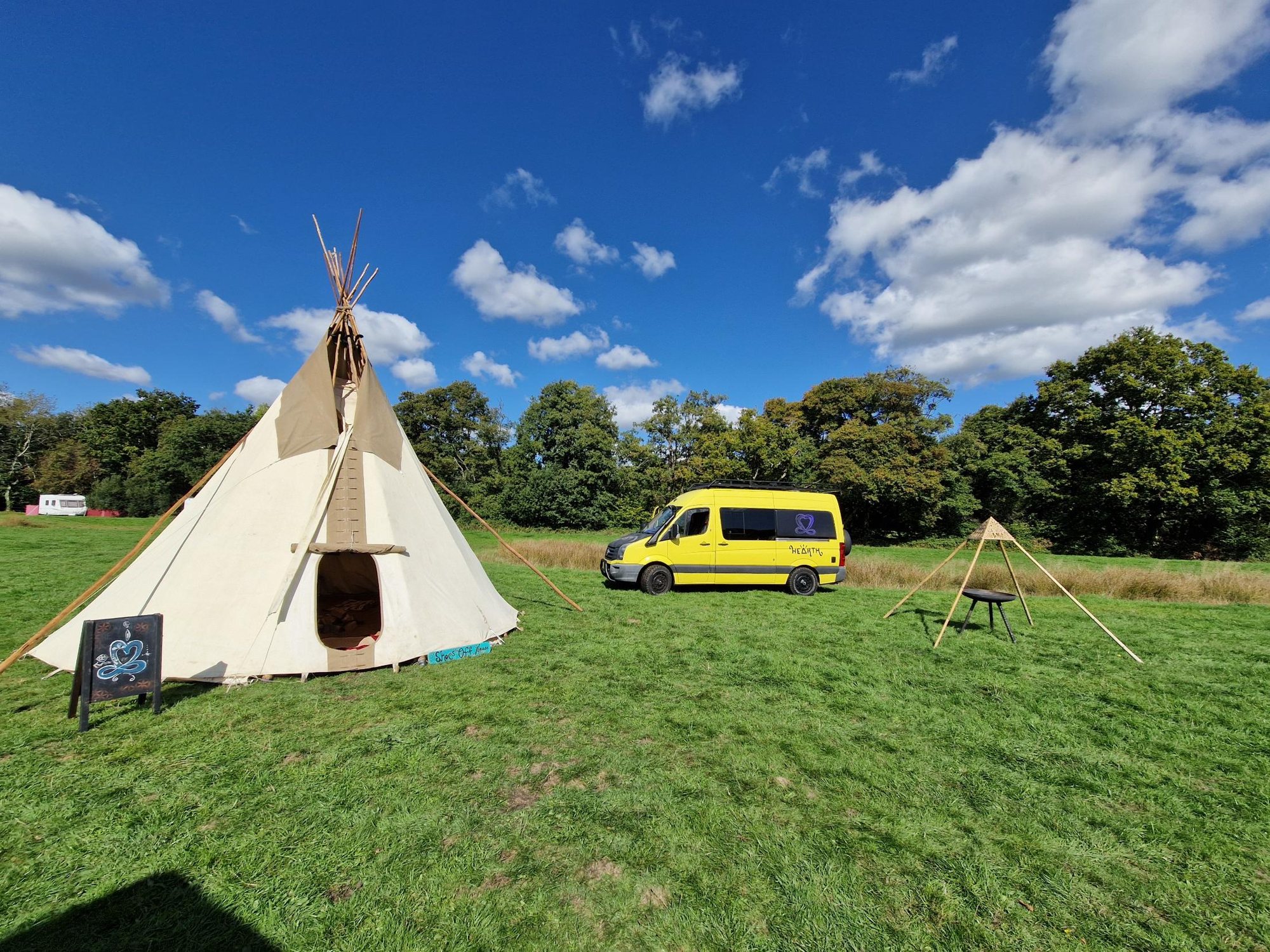 The tipi, the yellow HEARTH van and the fire bowl in the Dorset field