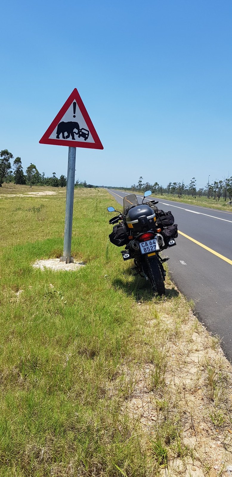 An adventure motorcycle beside an elephant road sign